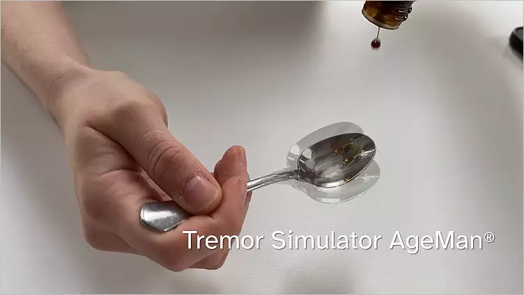 Link zu einem Video, in dem man Anwendungsbeispiele für den AgeMan Tremor-Simulator sieht, z.B. ein Medikament auf einen Löffel tropfen.