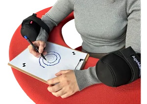Eine Person zeichnet eine Spirale nach. An ihren Unterarmen sind Tremor-Simulatoren befestigt, die Zittern auslösen.