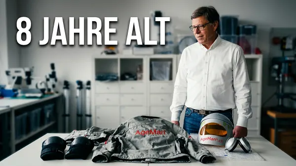 Ein zu prüfender Alterssimulationsanzug liegt auf dem Tisch, der Prüfer steht dahinter. Der Test kann beginnen.